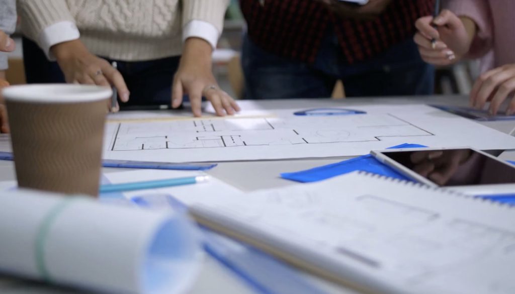 diverse-hands-with-pencils-discussing-and-working