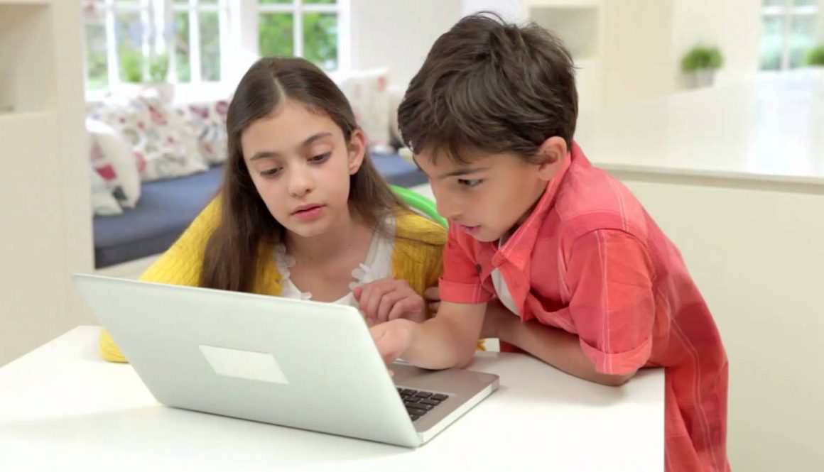 two-hispanic-children-using-laptop-at-home